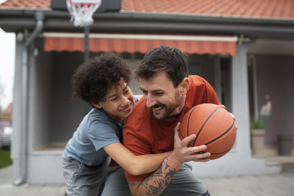 Father's Day Gifts That Actually Matter (2025 Guide) 11 Father and son playing basketball together at home in the backyard